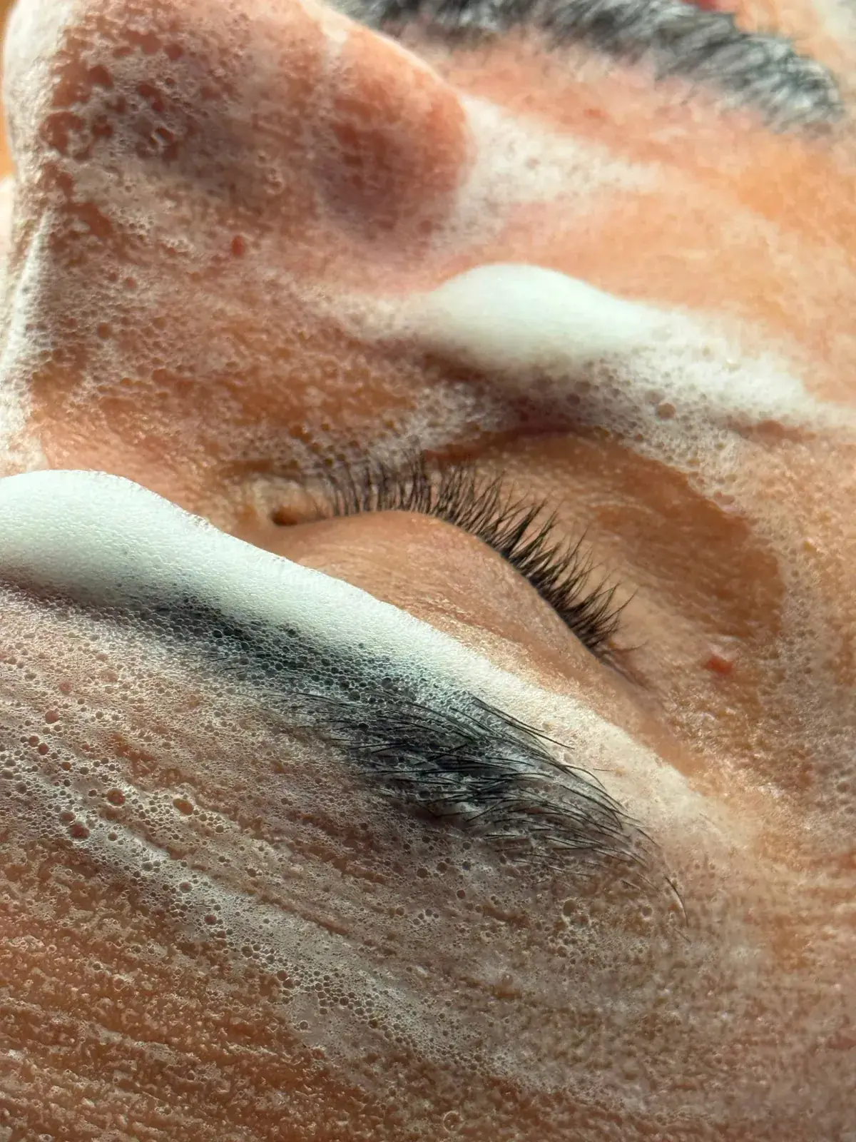 Detalhe de rosto com espuma de limpeza durante o ritual Hidratú no Espaço Matú